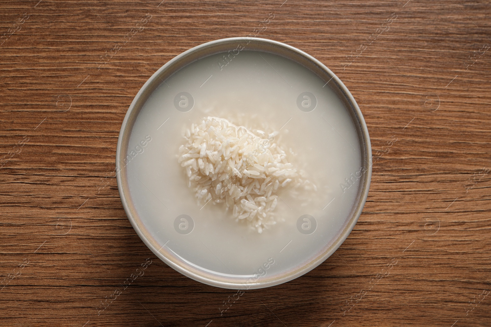 Photo of Rice soaked in water on wooden table, top view