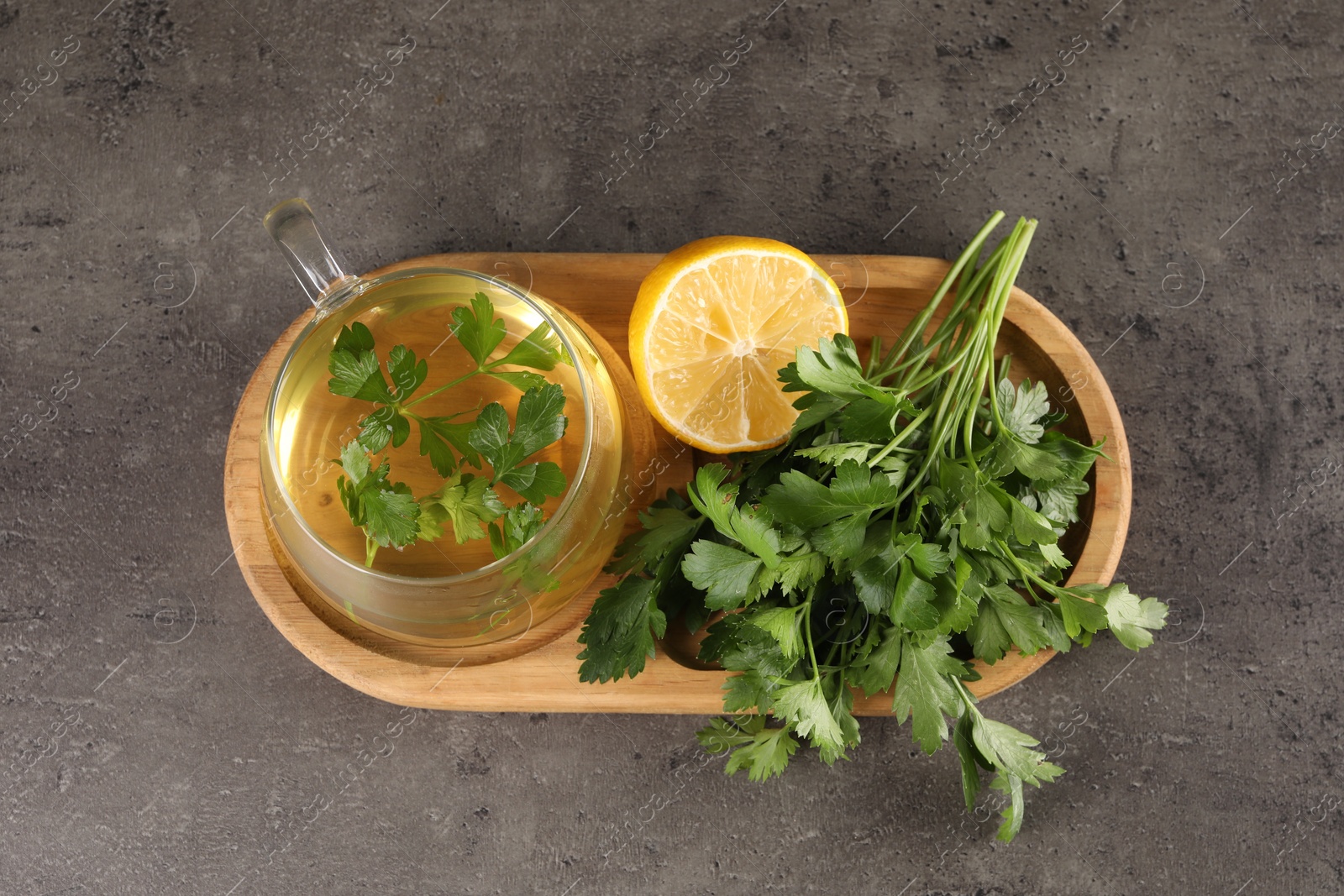 Photo of Aromatic herbal tea, fresh parsley and lemon on grey table, top view