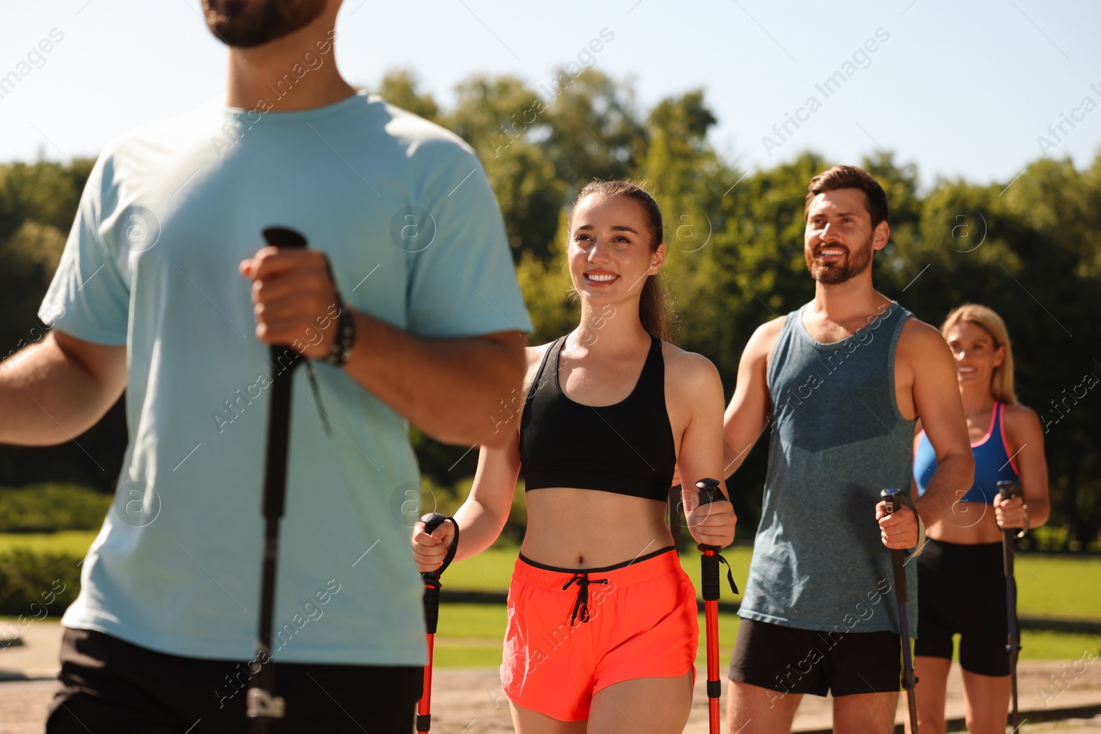 Photo of Group of people practicing Nordic walking with poles outdoors on sunny day