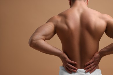 Photo of Man suffering from back pain on beige background, back view. Space for text
