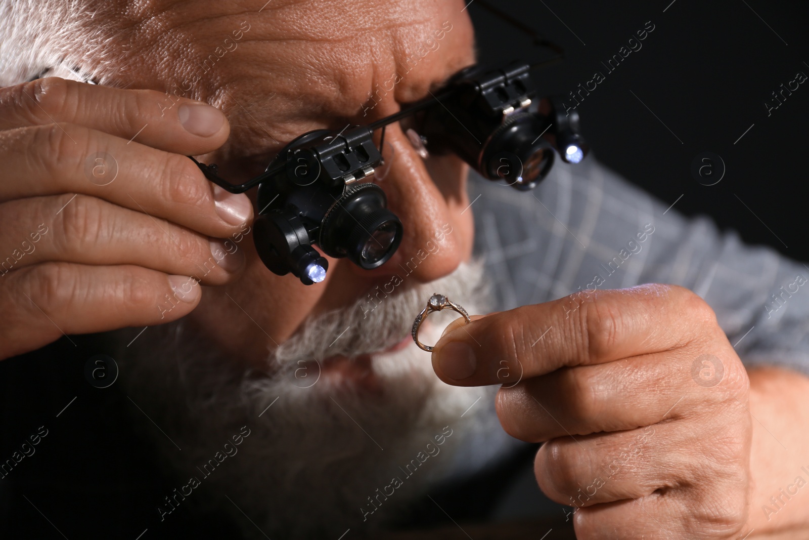 Photo of Male jeweler evaluating diamond ring in workshop, closeup view