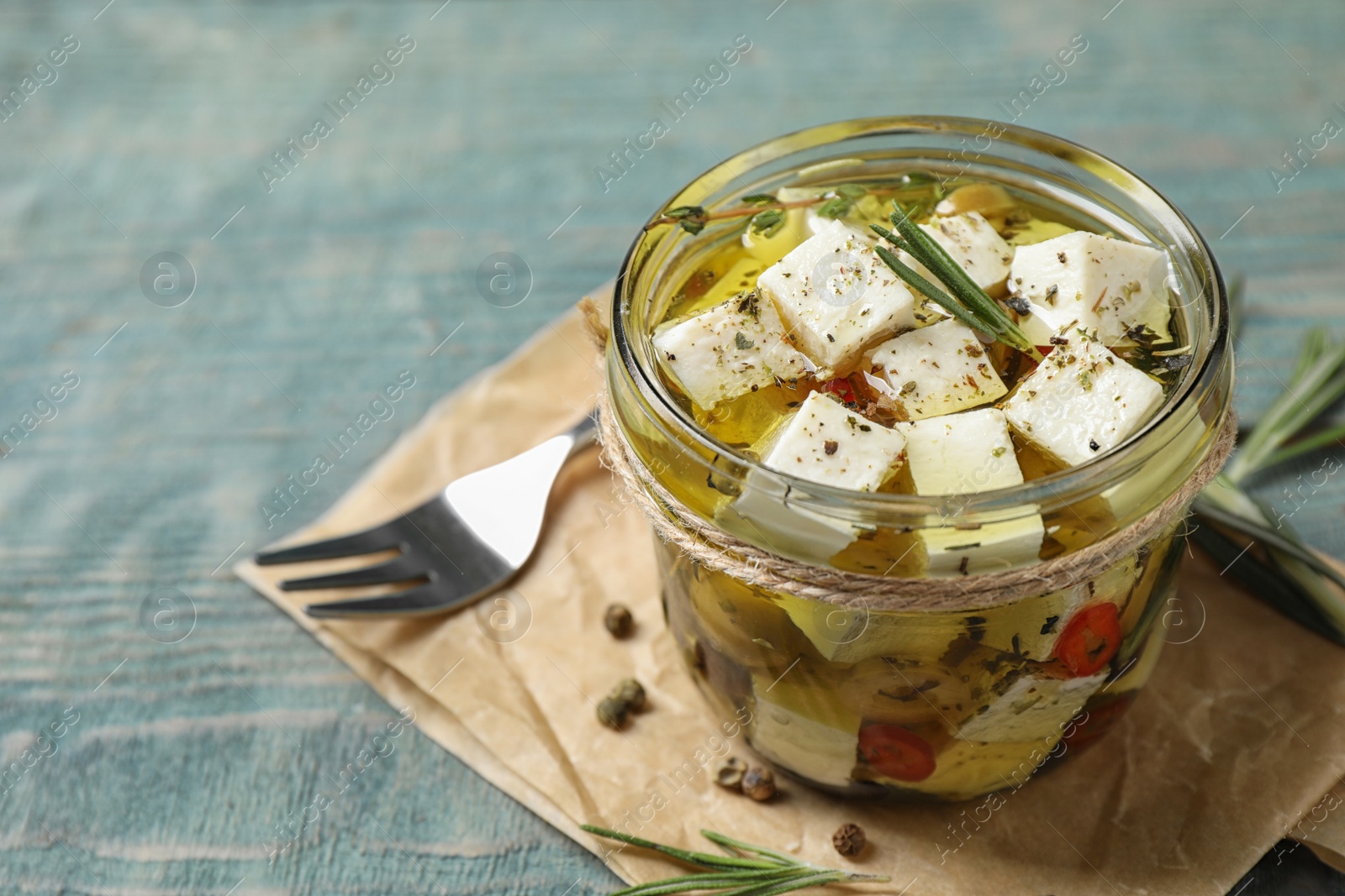 Photo of Composition with pickled feta cheese in jar on blue wooden table, space for text