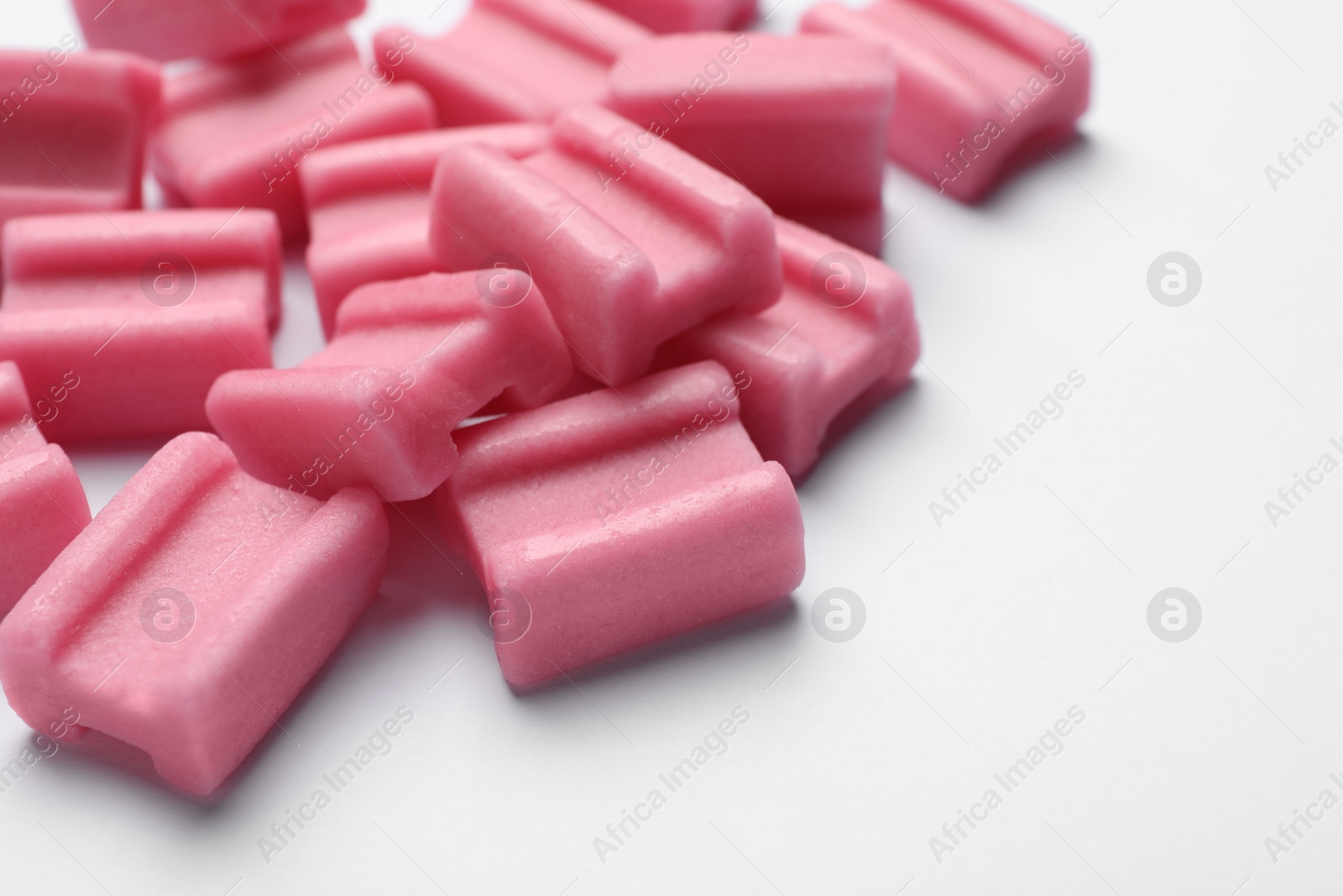 Photo of Tasty pink chewing gums on white background, closeup. Space for text