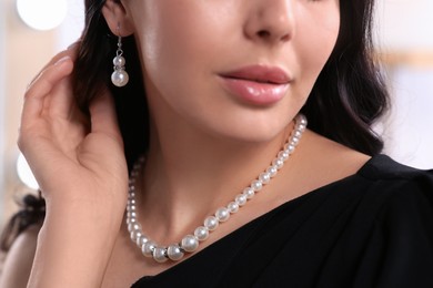Photo of Young woman wearing elegant pearl jewelry indoors, closeup