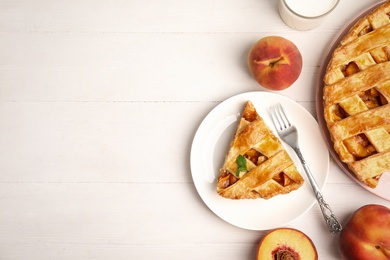 Photo of Delicious fresh peach pie served on white wooden table, flat lay. Space for text