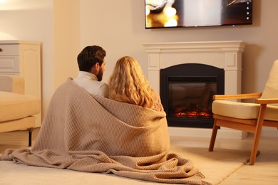 Photo of Lovely couple spending time together near fireplace at home, back view