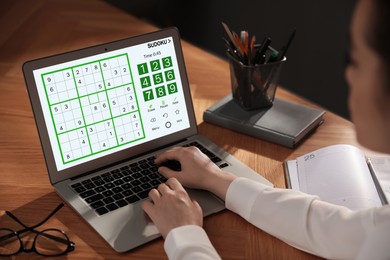 Woman playing sudoku game on laptop indoors, closeup