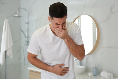 Photo of Man suffering from nausea in bathroom. Food poisoning