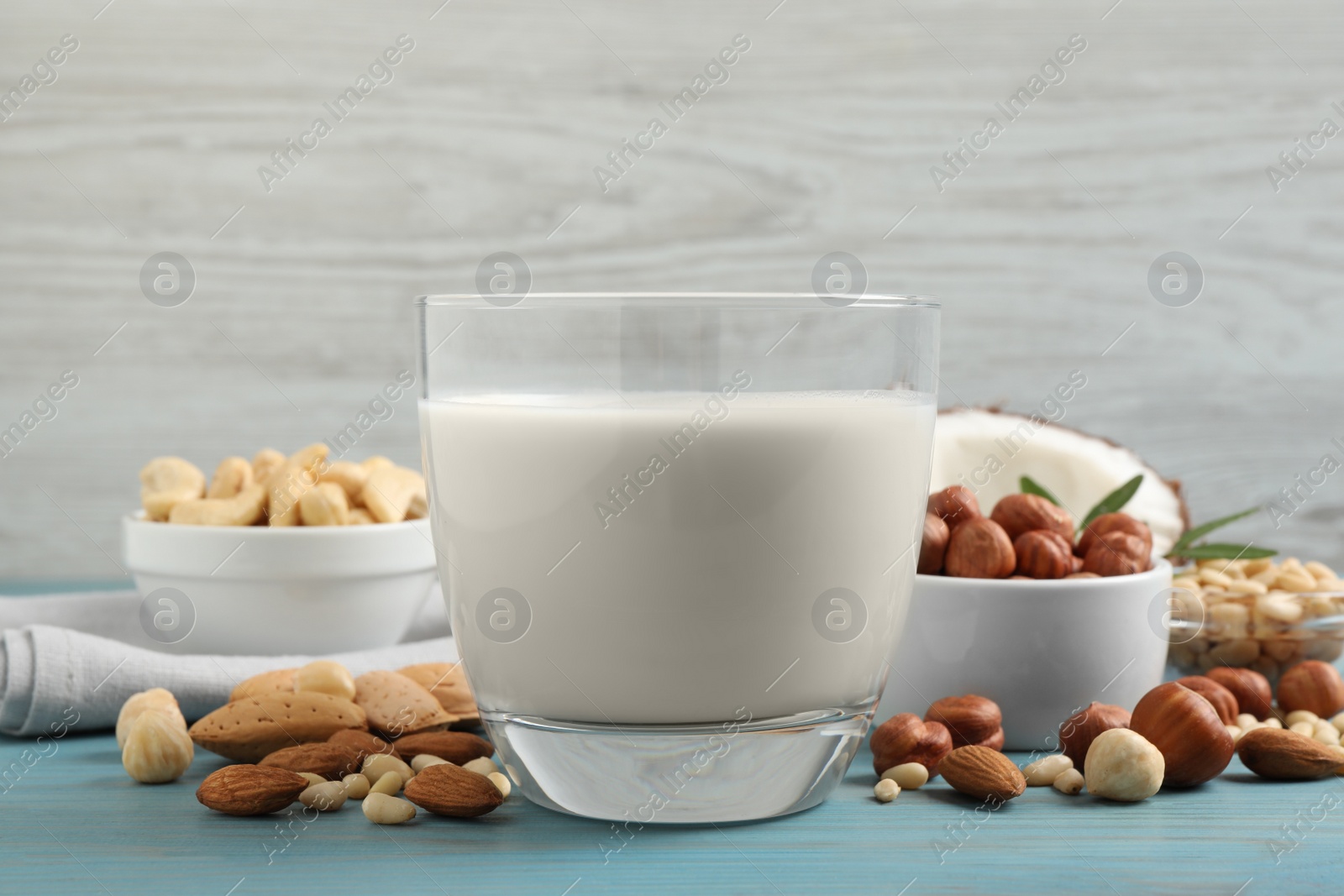 Photo of Vegan milk and different nuts on light blue wooden table