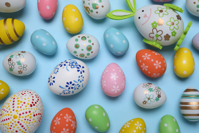 Colorful Easter eggs on light blue background, flat lay