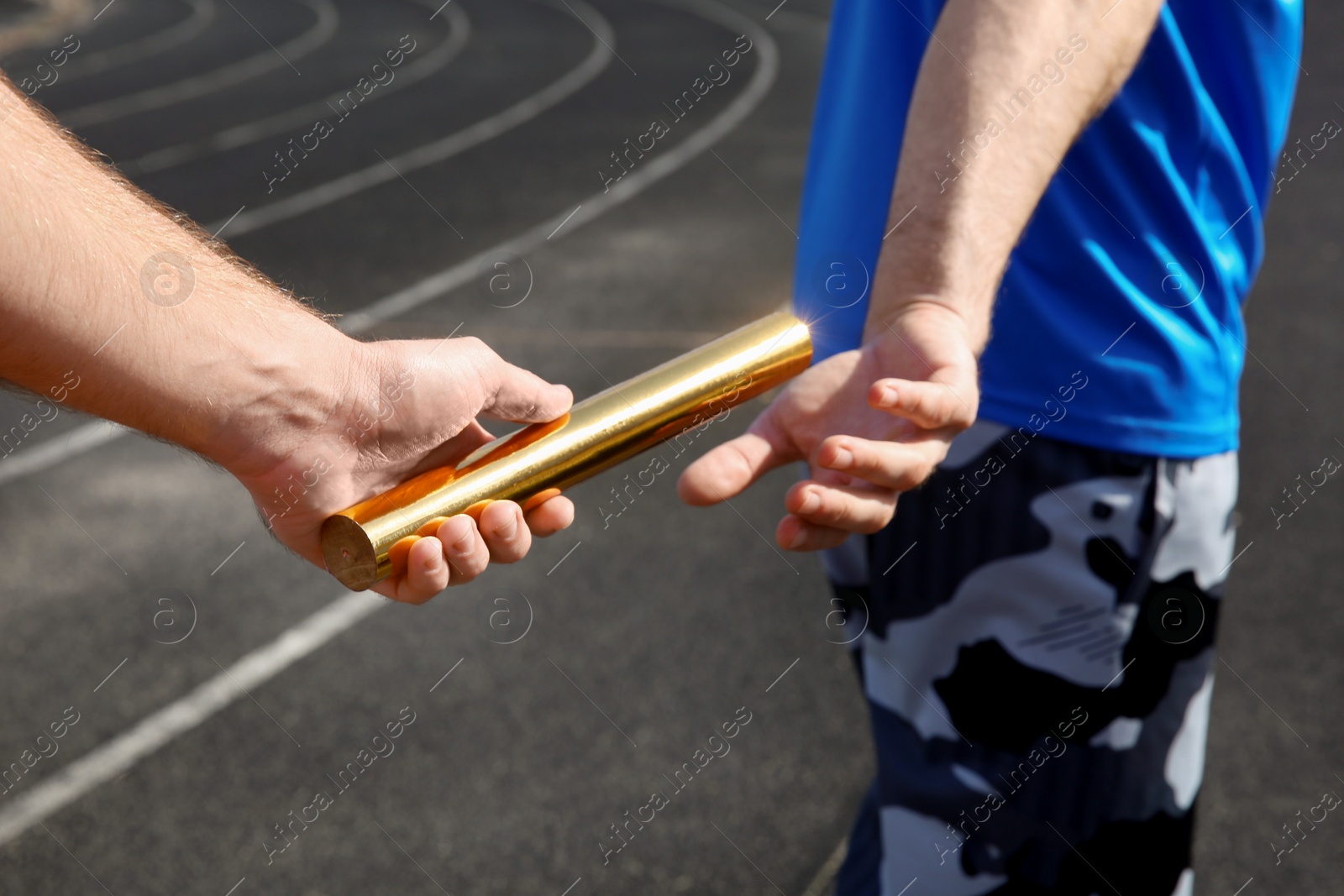 Photo of Man passing baton to his partner at stadium, closeup