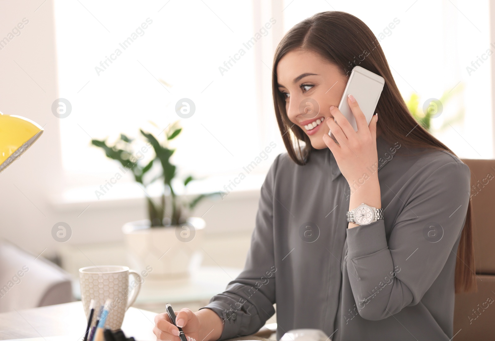 Photo of Young woman talking on phone at workplace