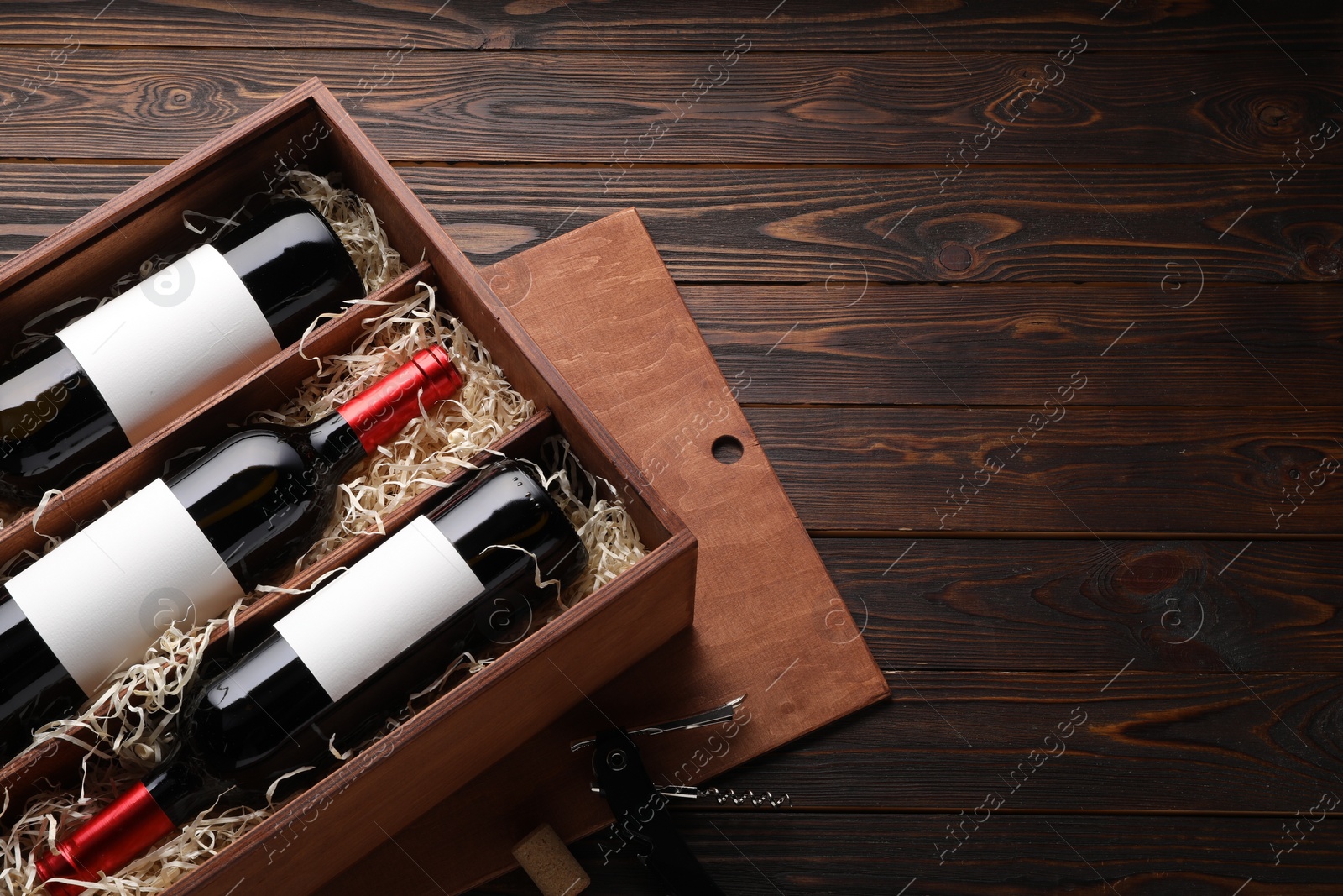 Photo of Box with wine bottles on wooden table, top view. Space for text