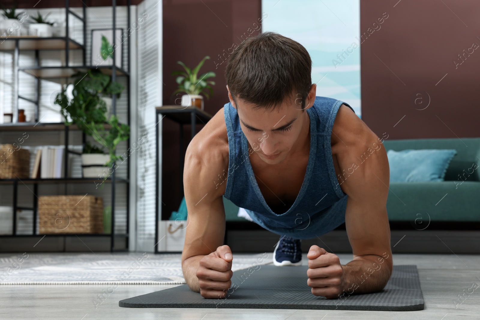 Photo of Handsome man doing plank exercise on floor at home