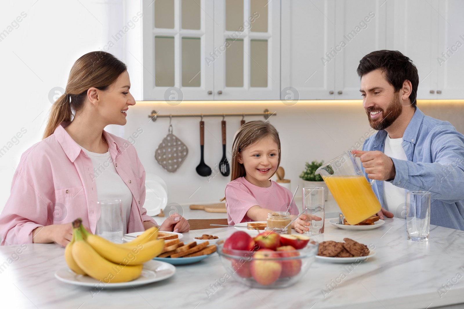 Photo of Happy family having breakfast at table in kitchen