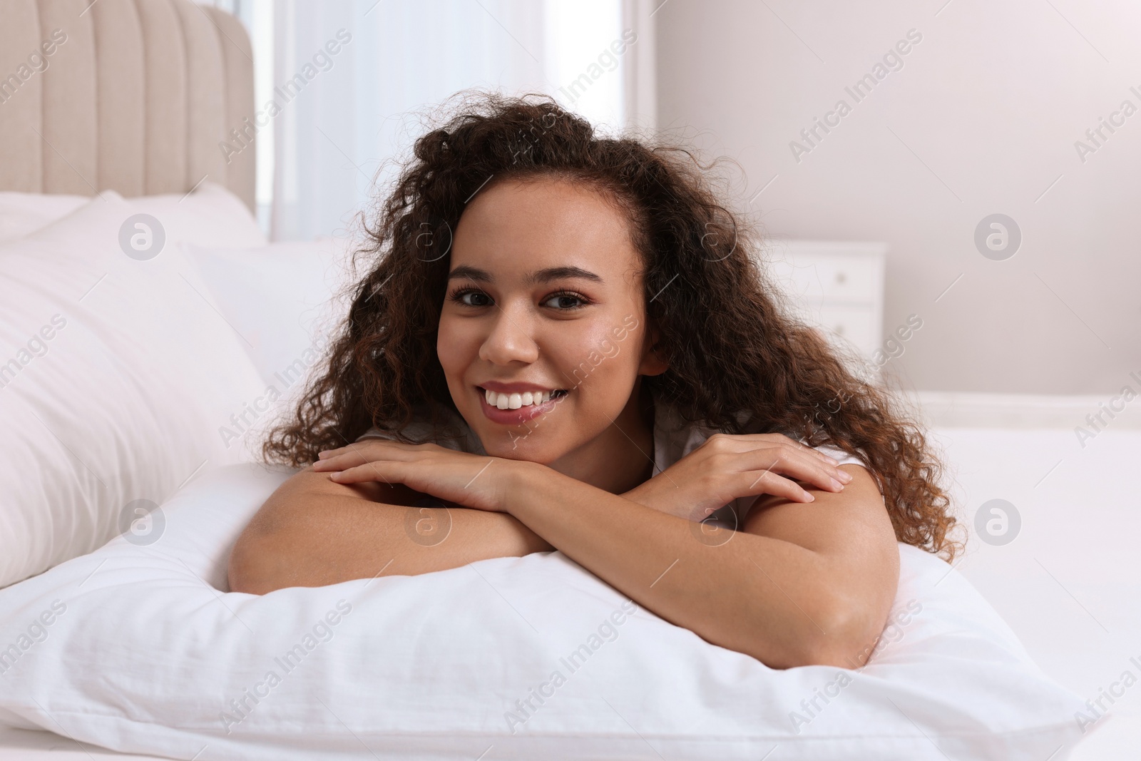 Photo of Happy African American woman lying on bed at home