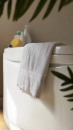 Photo of Soft fluffy towel hanging on bathtub indoors