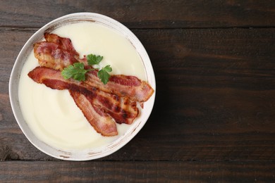 Delicious potato soup with bacon and parsley on wooden table, top view. Space for text