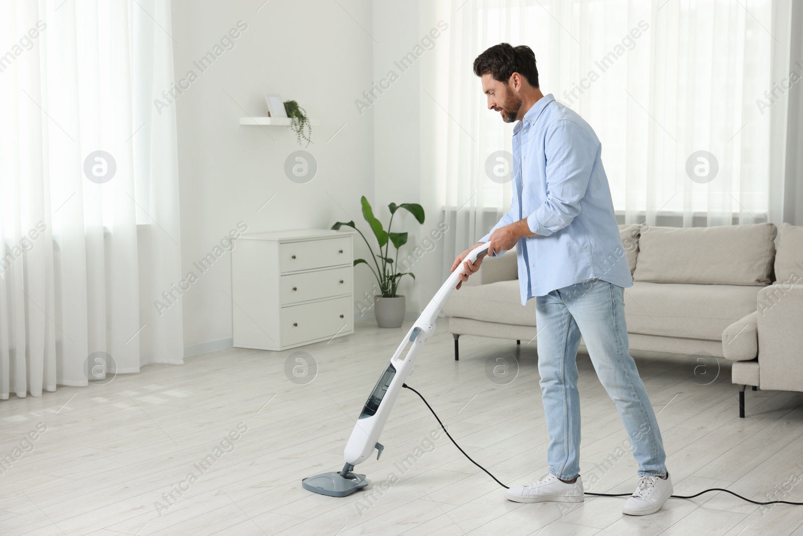 Photo of Man cleaning floor with steam mop at home. Space for text