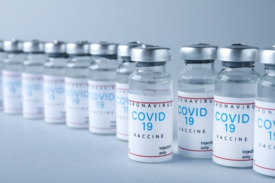 Vials with coronavirus vaccine on light grey background