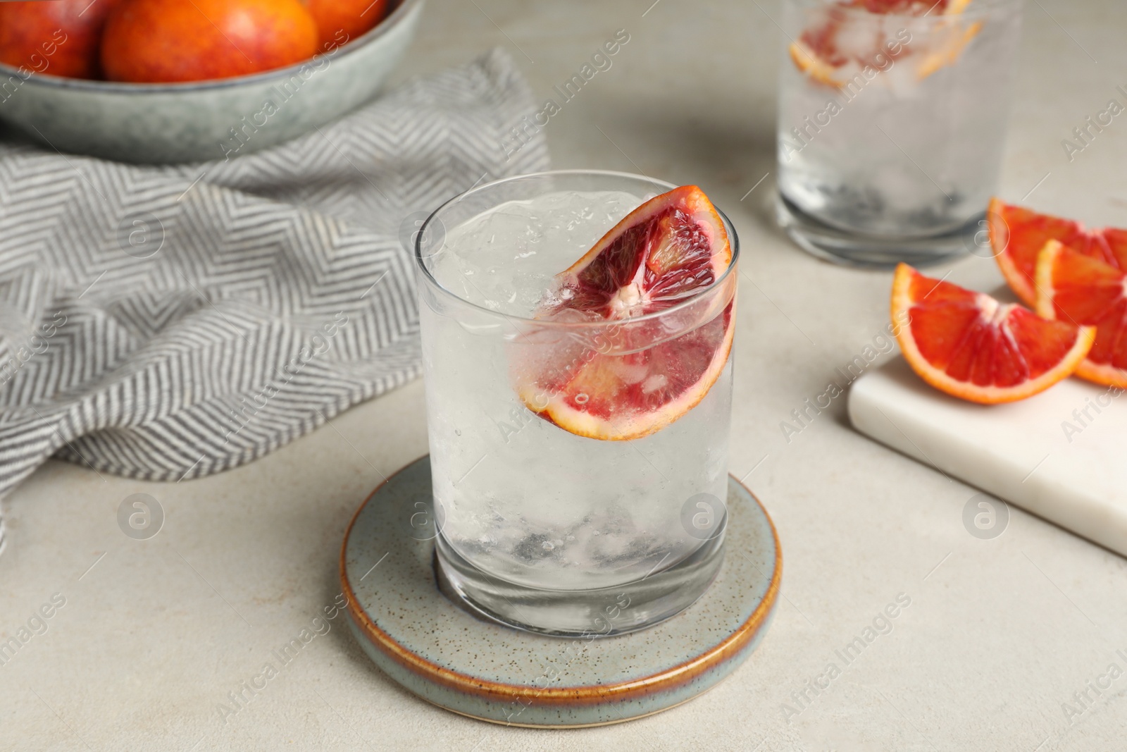 Photo of Delicious refreshing drink with sicilian orange and ice cubes on light table