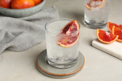 Photo of Delicious refreshing drink with sicilian orange and ice cubes on light table