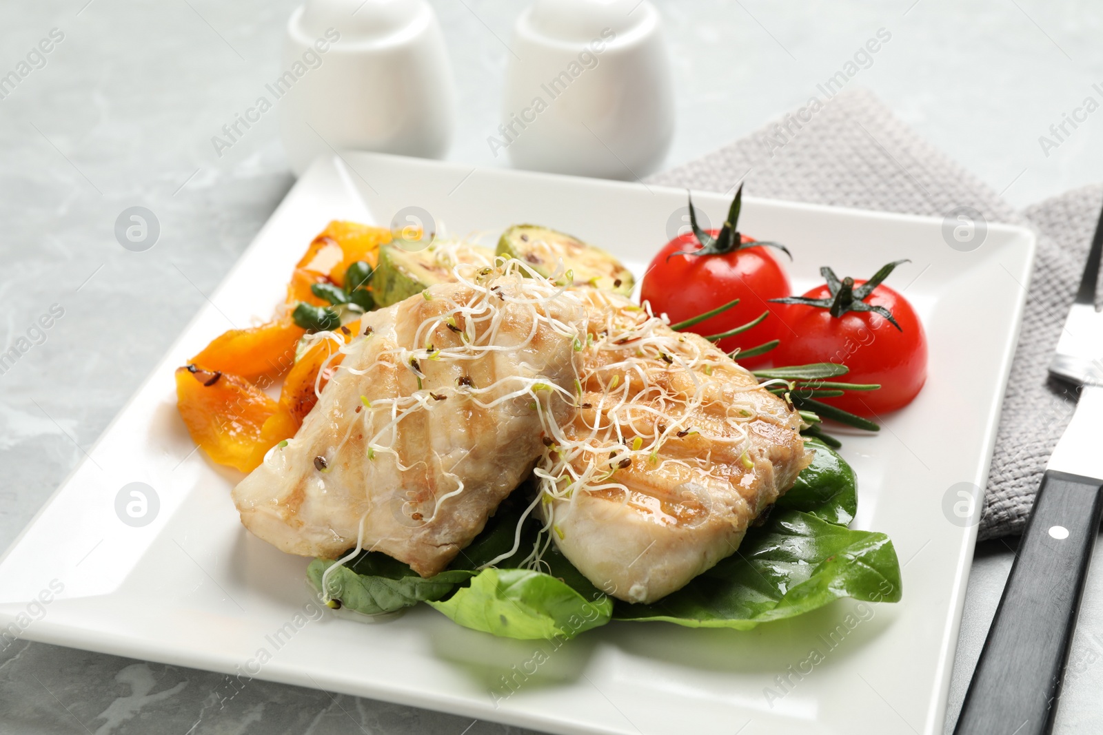 Photo of Tasty grilled fish served on light grey marble table