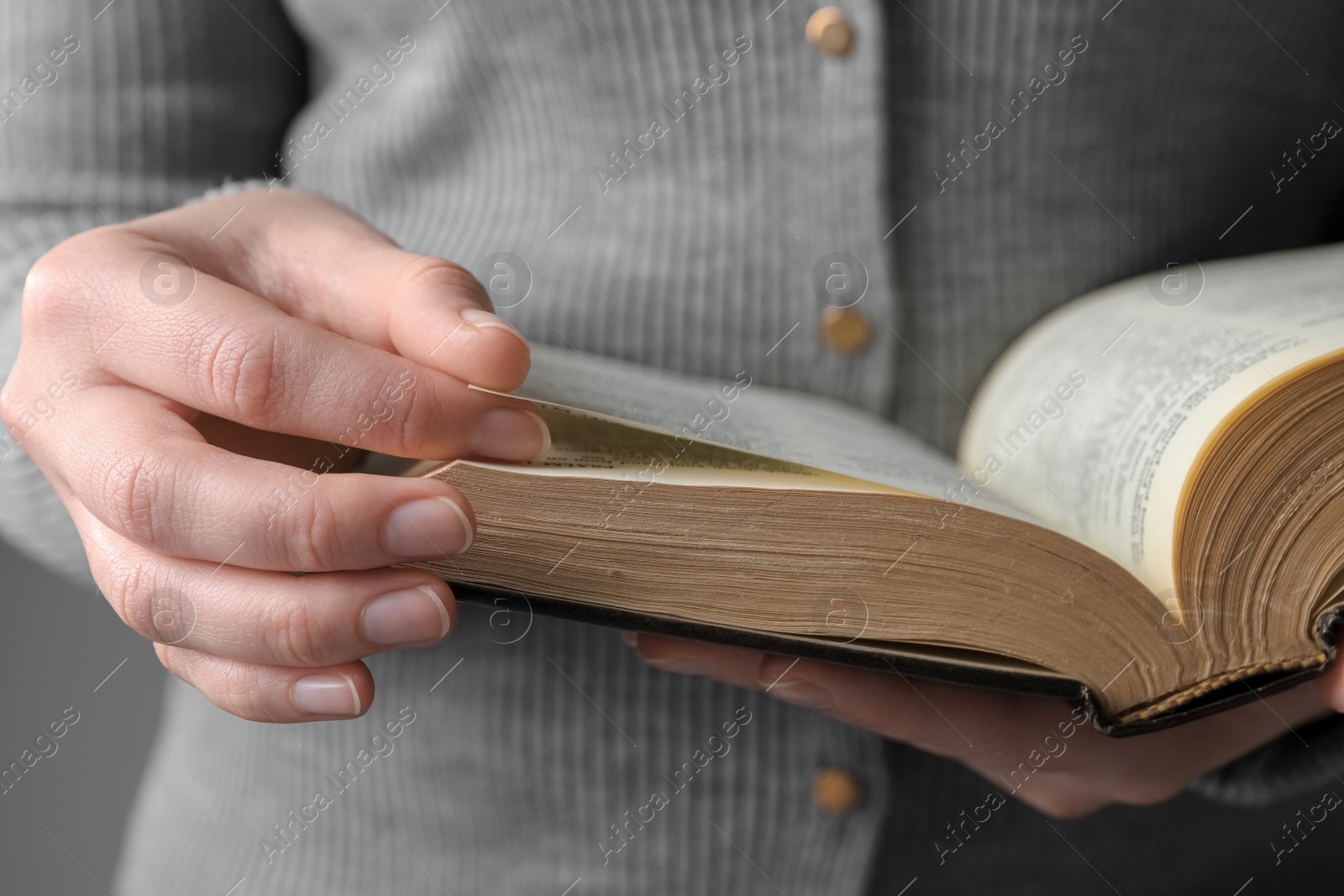 Photo of Woman reading Bible against grey background, closeup