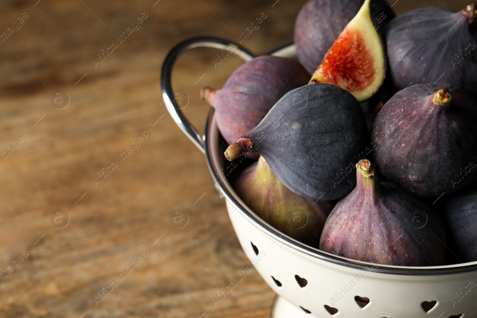 Photo of Tasty fresh figs in colander, closeup. Space for text