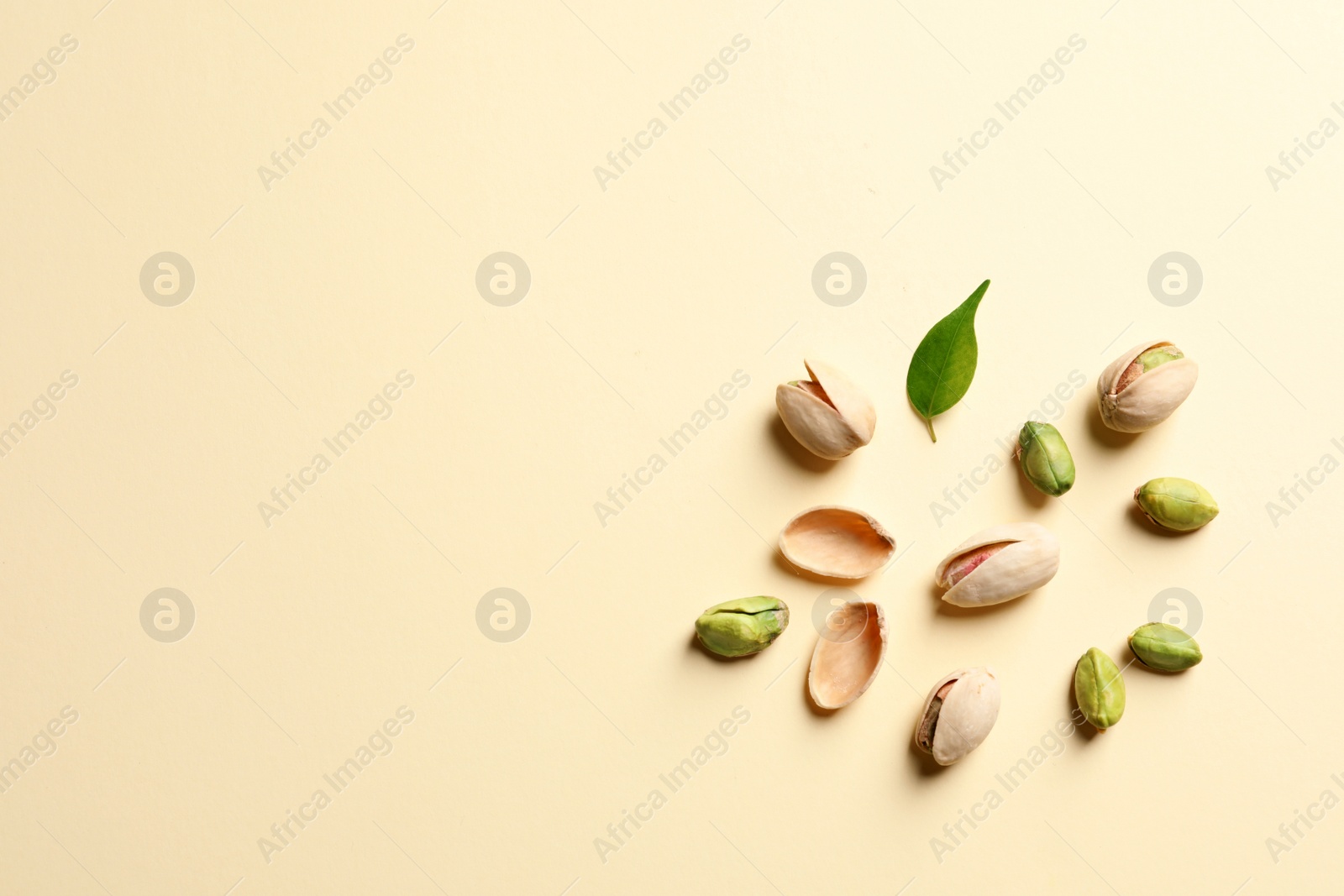 Photo of Composition with organic pistachio nuts on color background, flat lay. Space for text