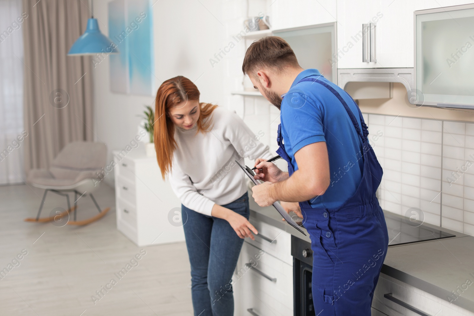 Photo of Housewife with repairman near modern oven in kitchen