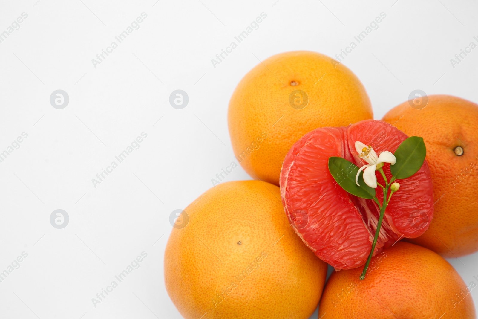 Photo of Fresh grapefruits and green leaves on white background, above view. Space for text