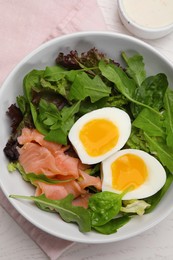 Delicious salad with boiled egg, salmon and arugula on white wooden table, flat lay