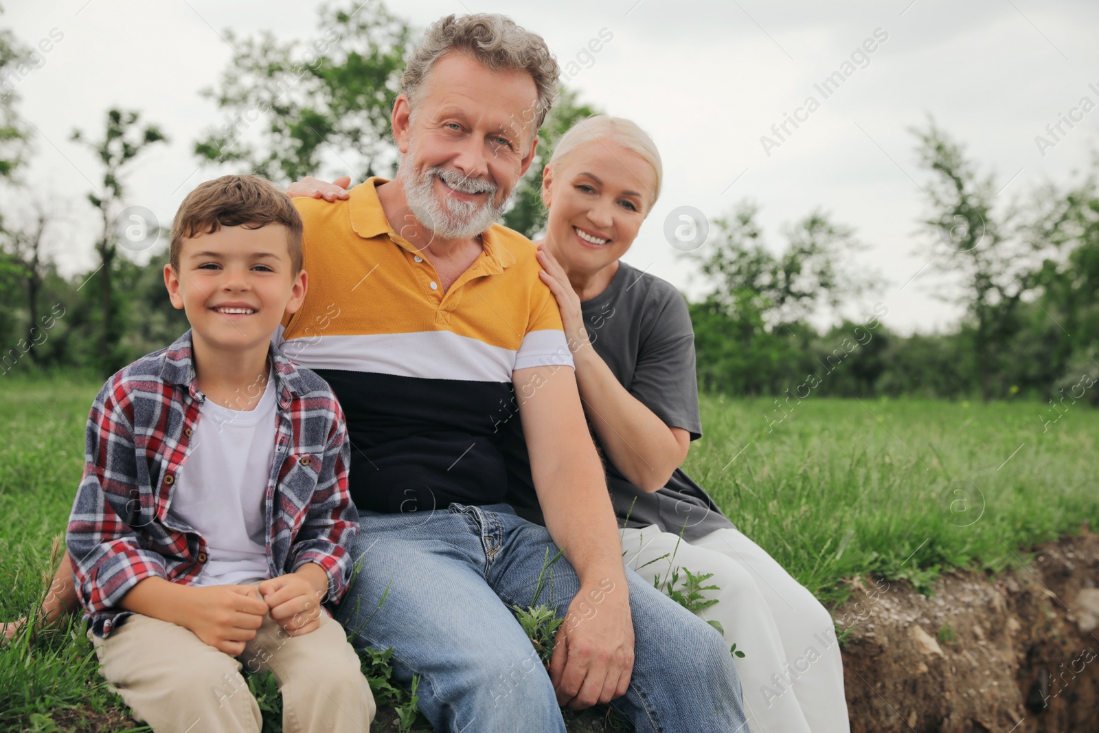 Photo of Cute little boy and grandparents spending time together in park