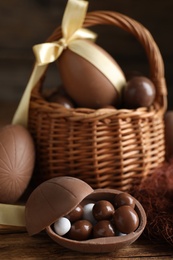 Tasty chocolate egg with candies on wooden table. Space for text