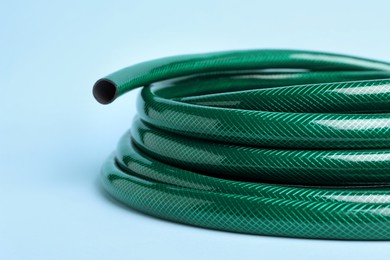 Photo of Watering hose on light blue background, closeup