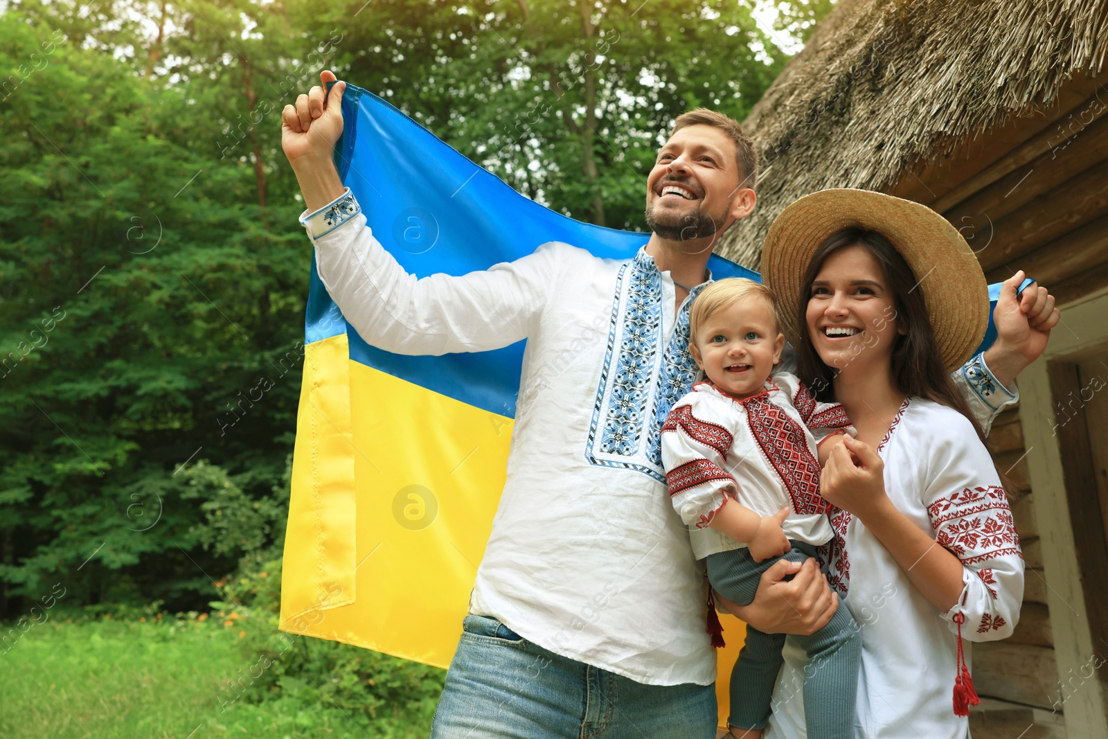 Photo of Happy family in national clothes with flag of Ukraine outdoors