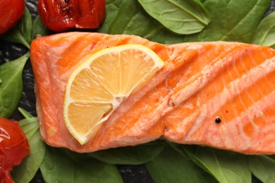 Tasty grilled salmon with tomatoes, spinach and lemon on table, top view