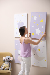 Photo of Decorator hanging picture on pink wall. Children's room interior design