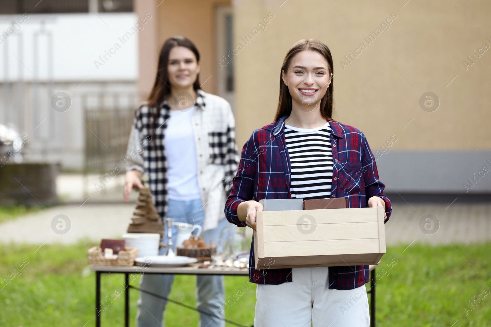 Photo of Women organize garage sale with different items in yard