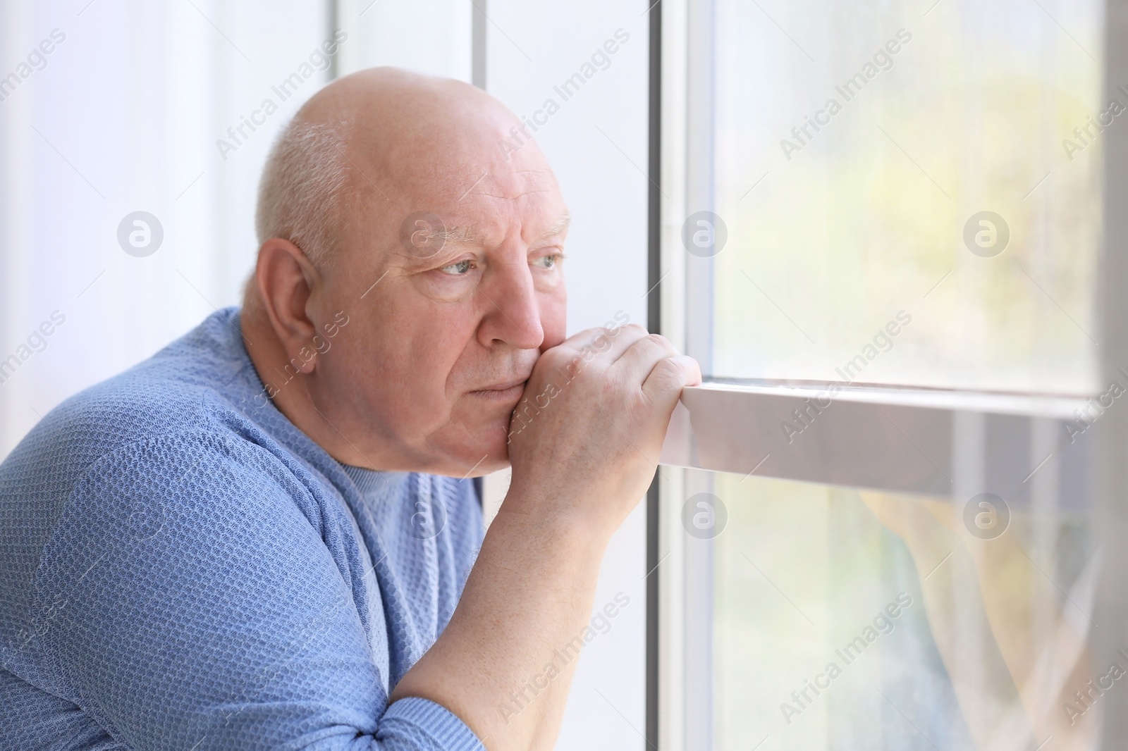 Photo of Depressed senior man near window indoors