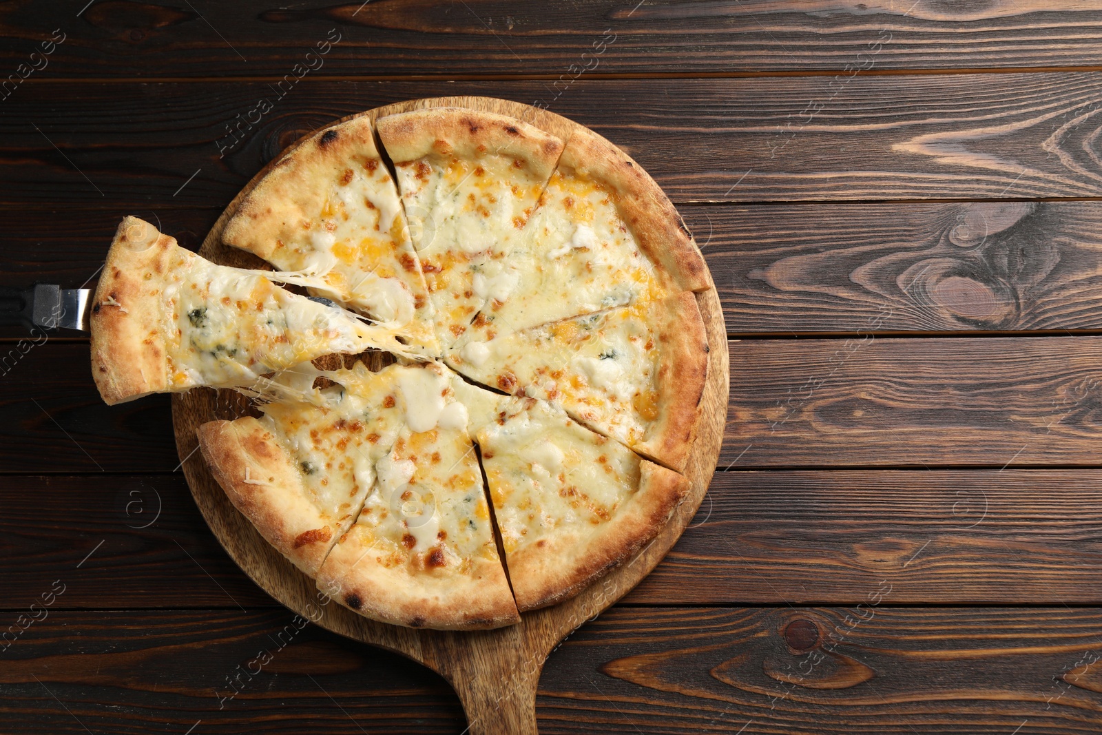 Photo of Taking piece of delicious cheese pizza at wooden table, top view. Space for text