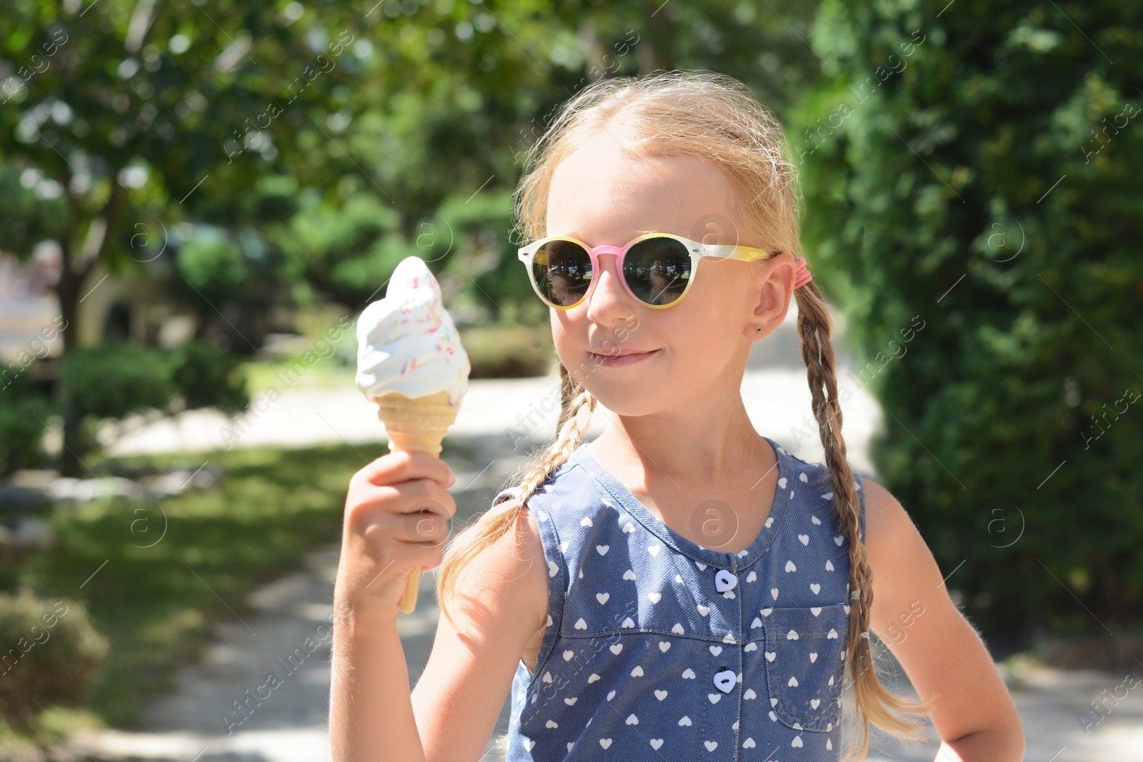 Photo of Adorable little girl with delicious ice cream outdoors on sunny summer day