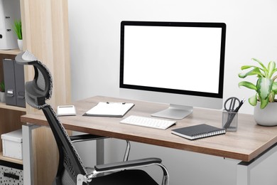 Image of Comfortable workplace at home. Modern computer with blank screen and stationery on wooden desk. Mockup for design