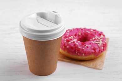 Tasty frosted donut and hot drink on white wooden table