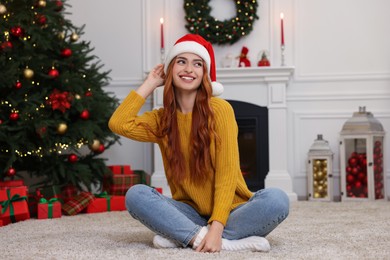 Photo of Beautiful young woman wearing Santa hat in room decorated for Christmas