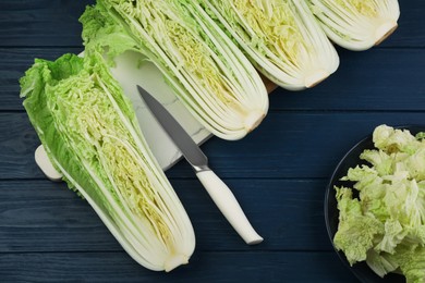 Photo of Cut fresh ripe Chinese cabbages on blue wooden table, flat lay