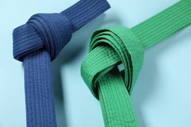 Photo of Colorful karate belts on light blue background, closeup