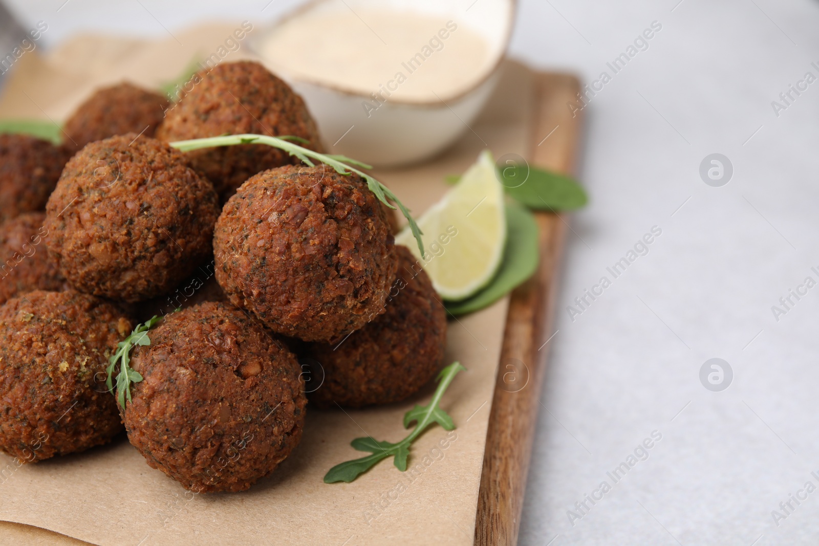 Photo of Delicious falafel balls and arugula on light table, closeup. Space for text