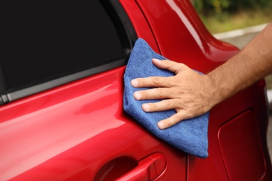 Photo of Man cleaning red auto with duster, closeup. Car wash service